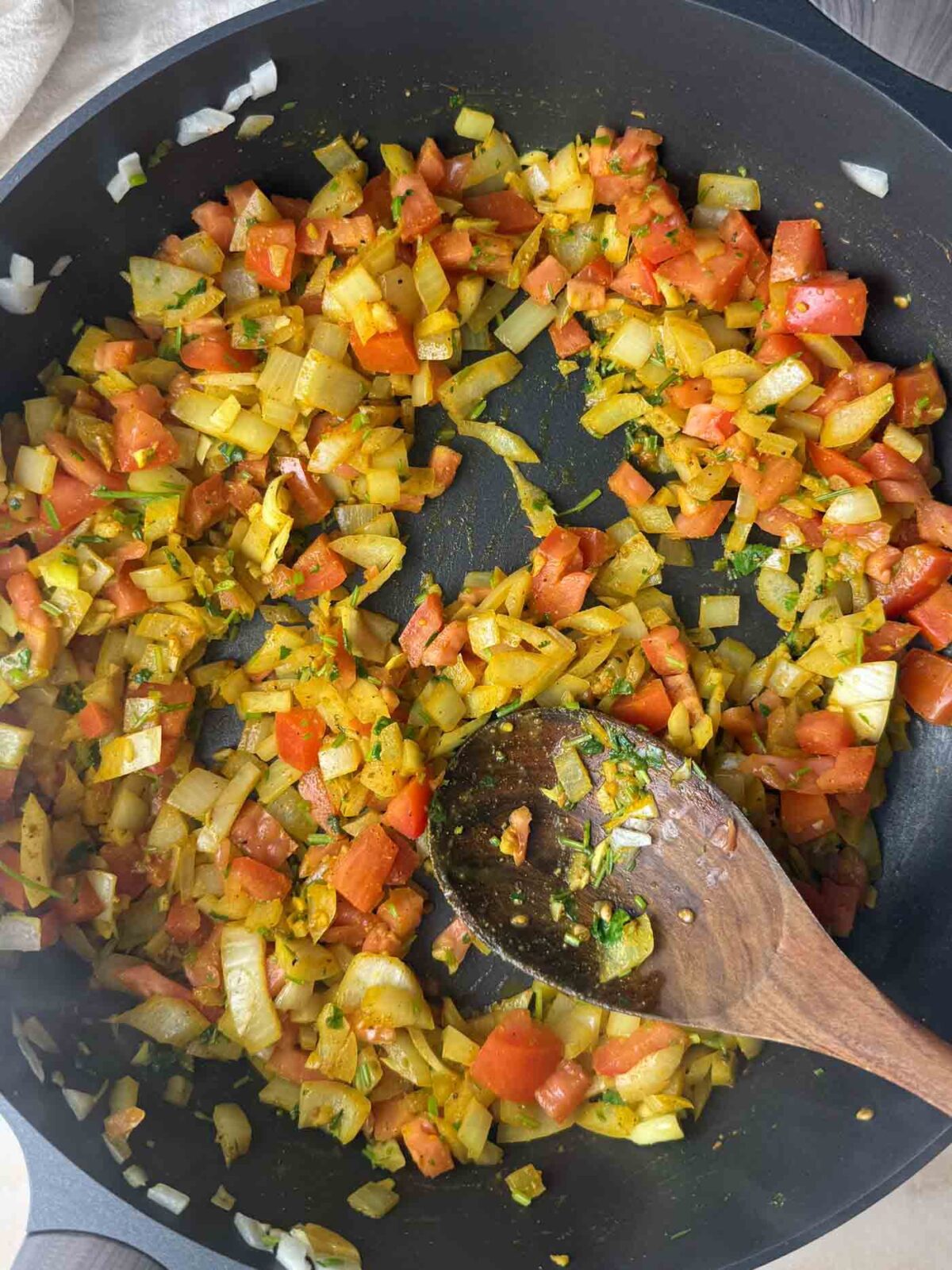 Onions and tomato coated in turmeric and warm spices as they toast in oil.