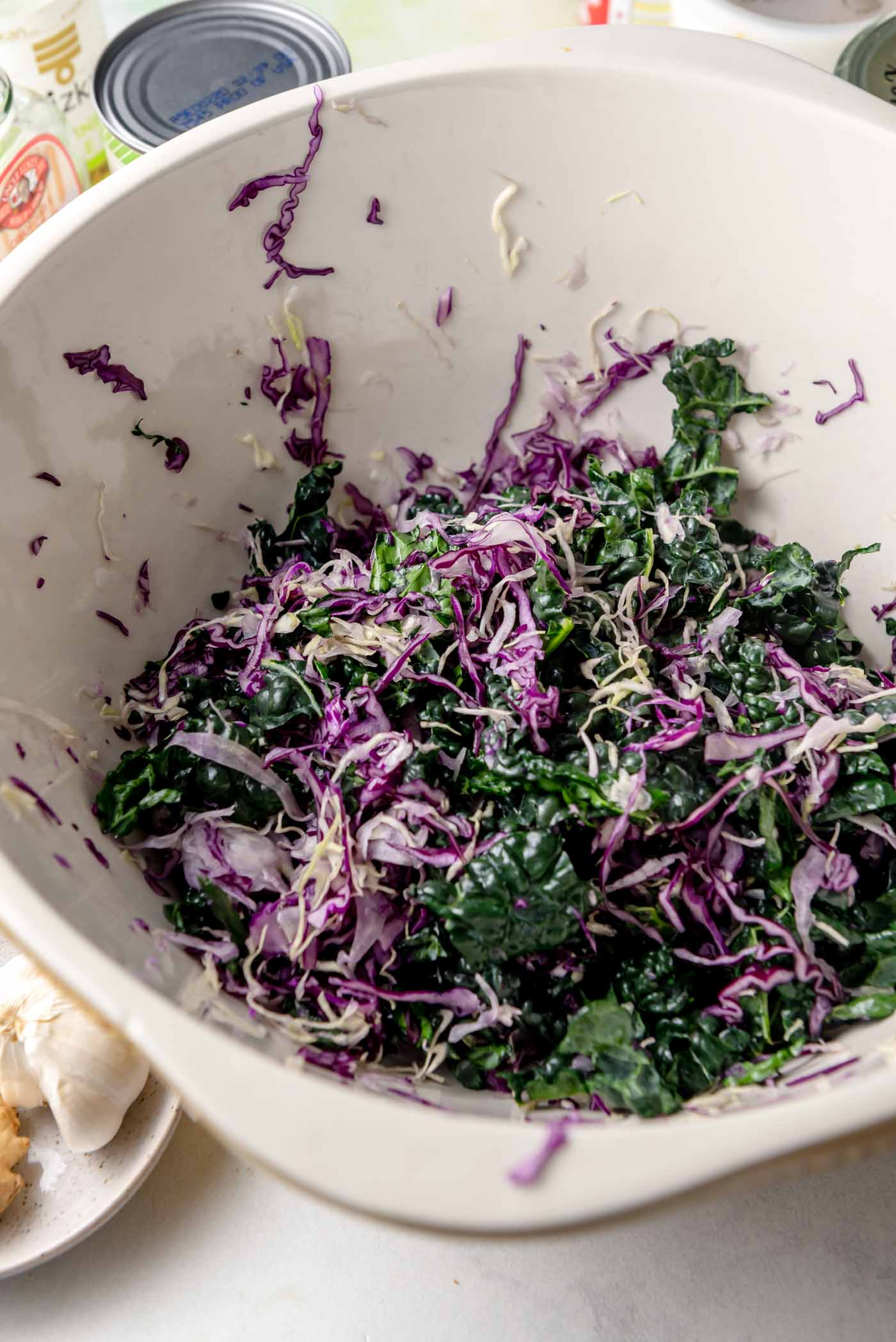 Shredded kale and red cabbage in a large mixing bowl, lightly massaged and ready for salad assembly.