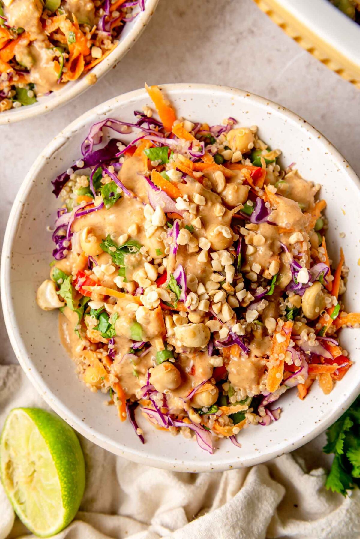 Thai peanut quinoa salad served in a bowl, topped with chopped peanuts and cashews and finished with a squeeze of fresh lime.