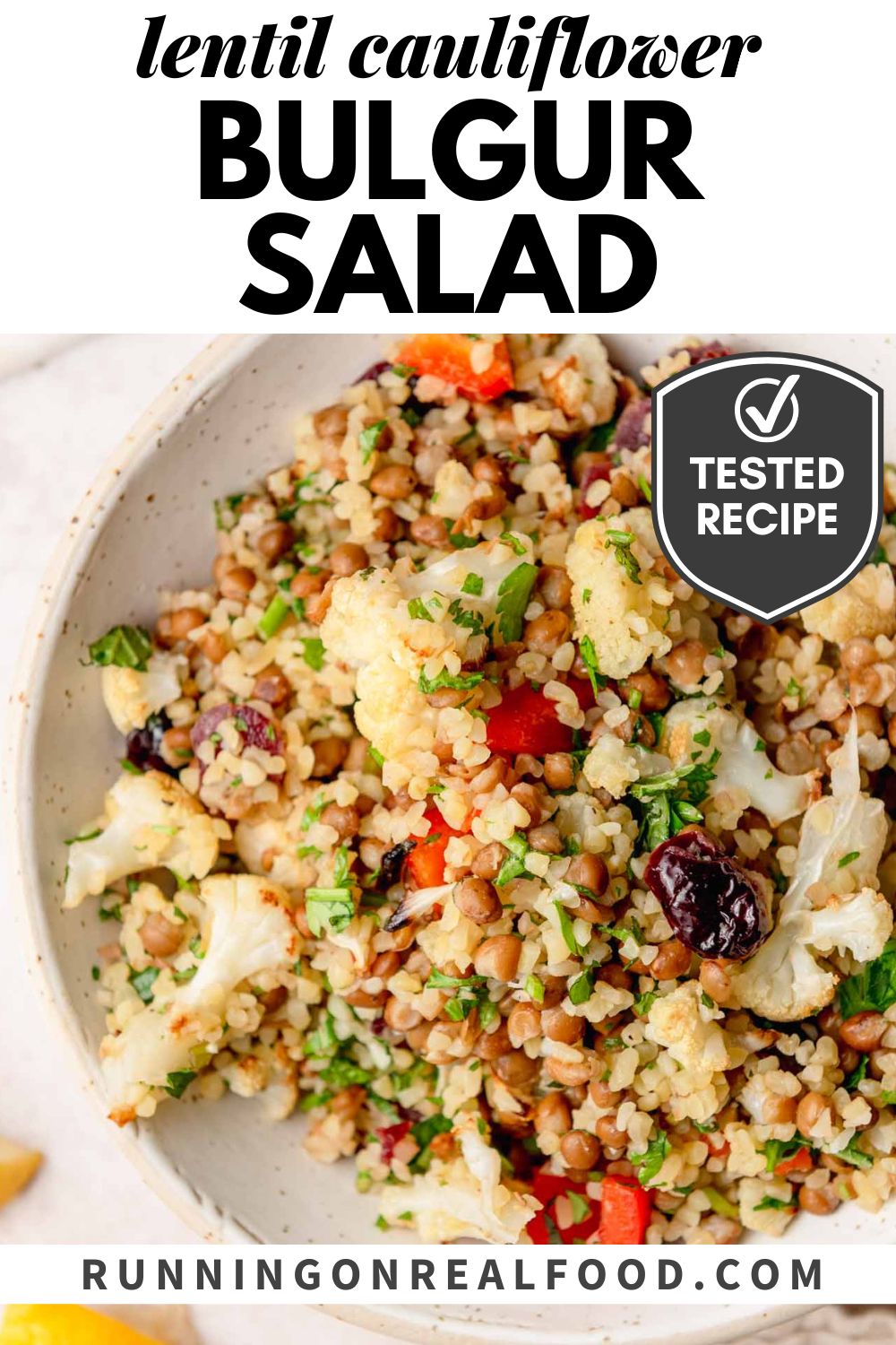 Overhead close-up of bulgur salad with lentils, roasted cauliflower, red bell pepper, fresh herbs and dried cranberries in a white bowl, with text reading “lentil cauliflower bulgur salad” and a tested recipe badge.